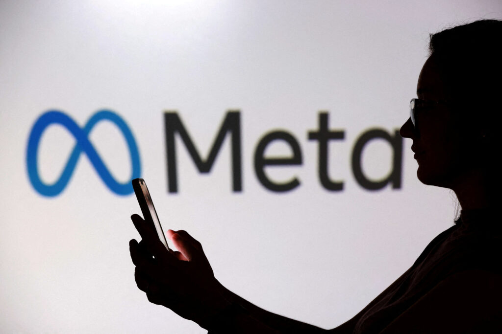 FILE PHOTO: A teenager poses for a photo while holding a smartphone in front of a Meta logo in this illustration taken September 11, 2025. REUTERS/Dado Ruvic/Illustration/File Photo